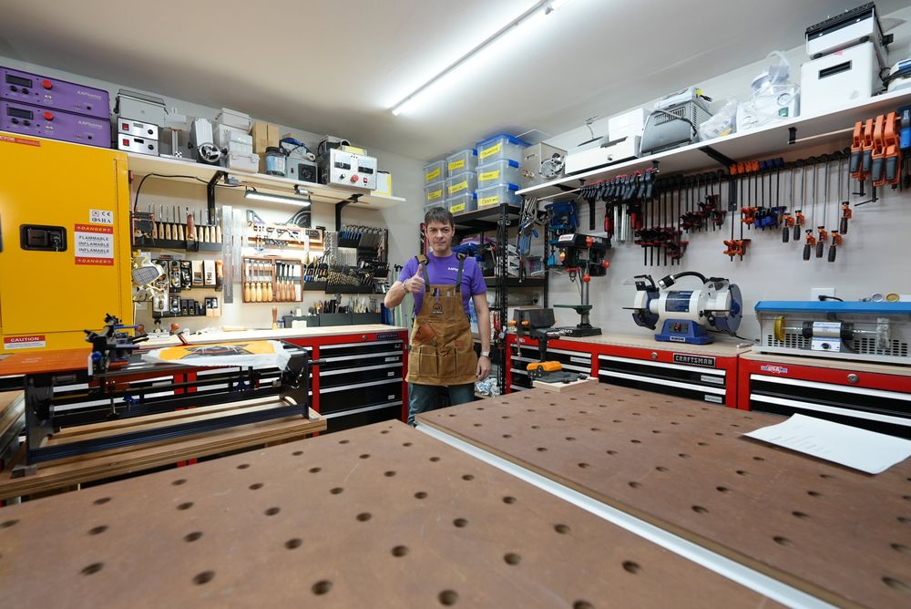 Greg giving a thumbs up in Gogga's Workshop, surrounded by tool chests, clamps, and workshop equipment